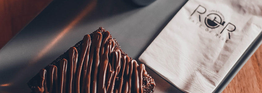 Eine bedruckte Serviette mit Logo liegt neben einem Stück Kuchen auf einer Foodmesse